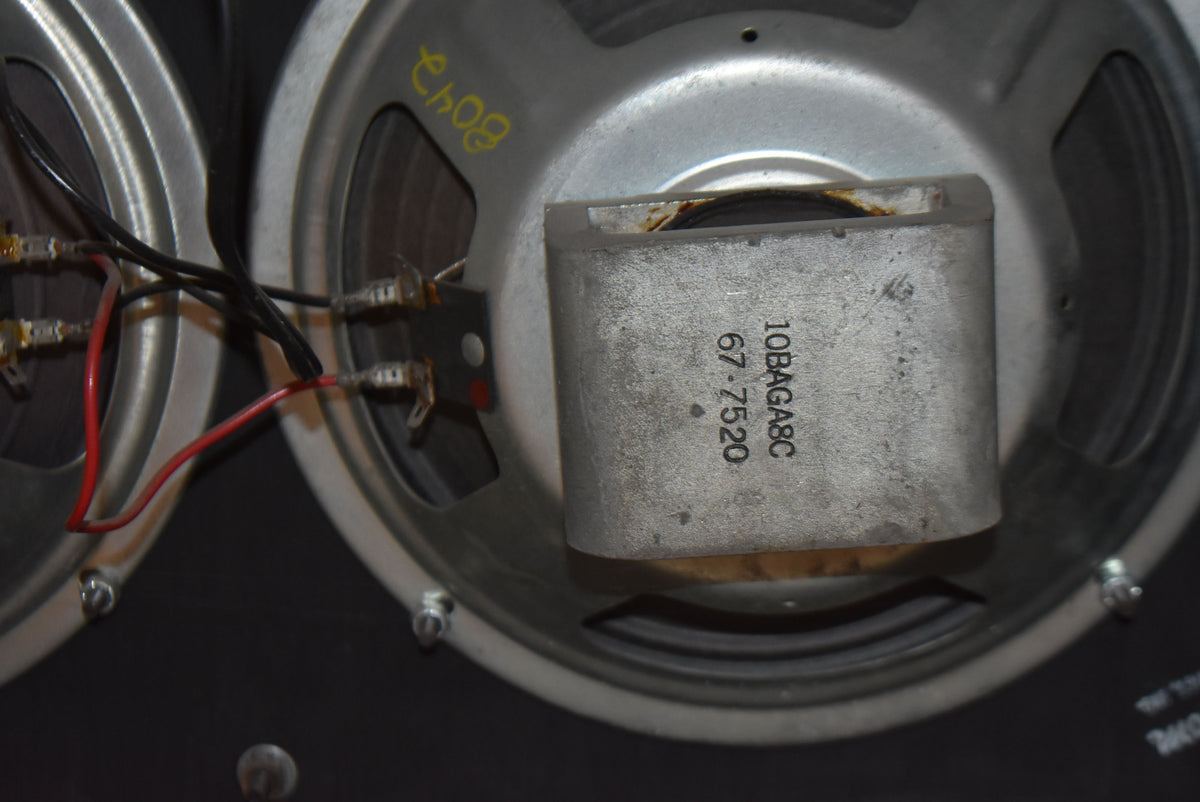 Close-up of two silver-coned speakers, showing wiring, mounting screws, and a magnet with "10BAGABC 67-7520" printed on it.