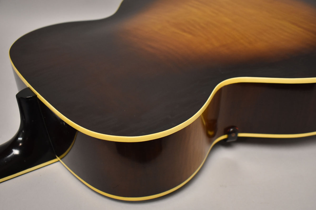 Close-up of the guitar's lower bout and cutaway, showing the dark sunburst finish, cream binding, and a strap button.