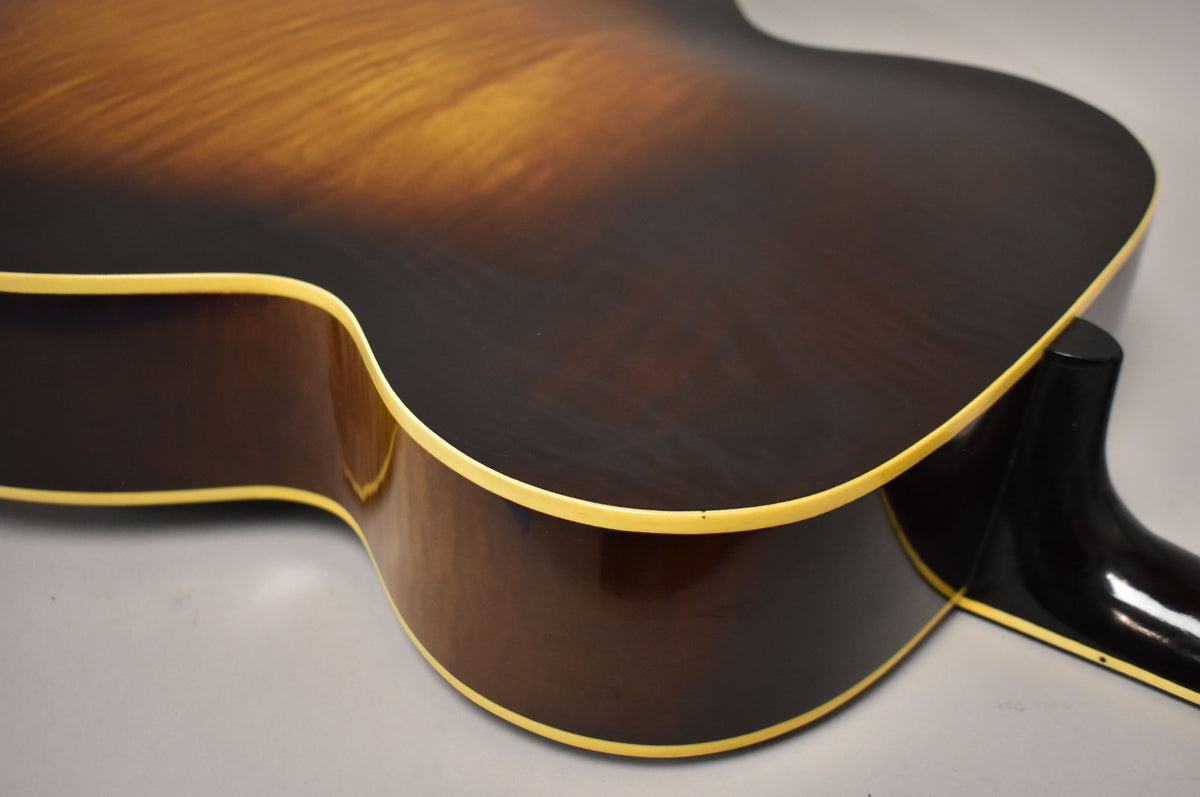 Close-up of the guitar's lower bout and cutaway, showing the dark sunburst finish, cream binding, and some minor wear.