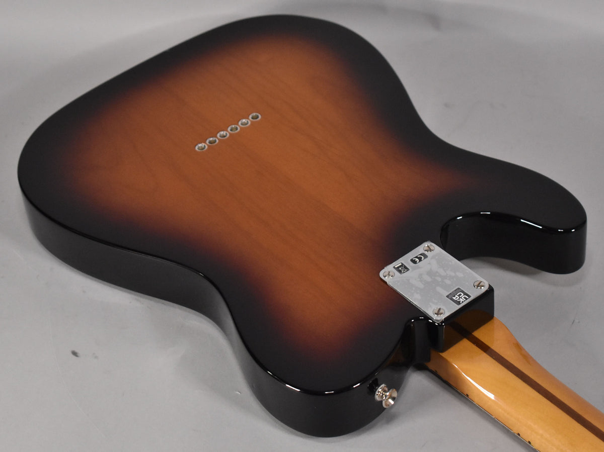 The guitar's back, in a glossy 2-color sunburst, shows six string ferrules, a chrome neck plate, and a light wood neck.
