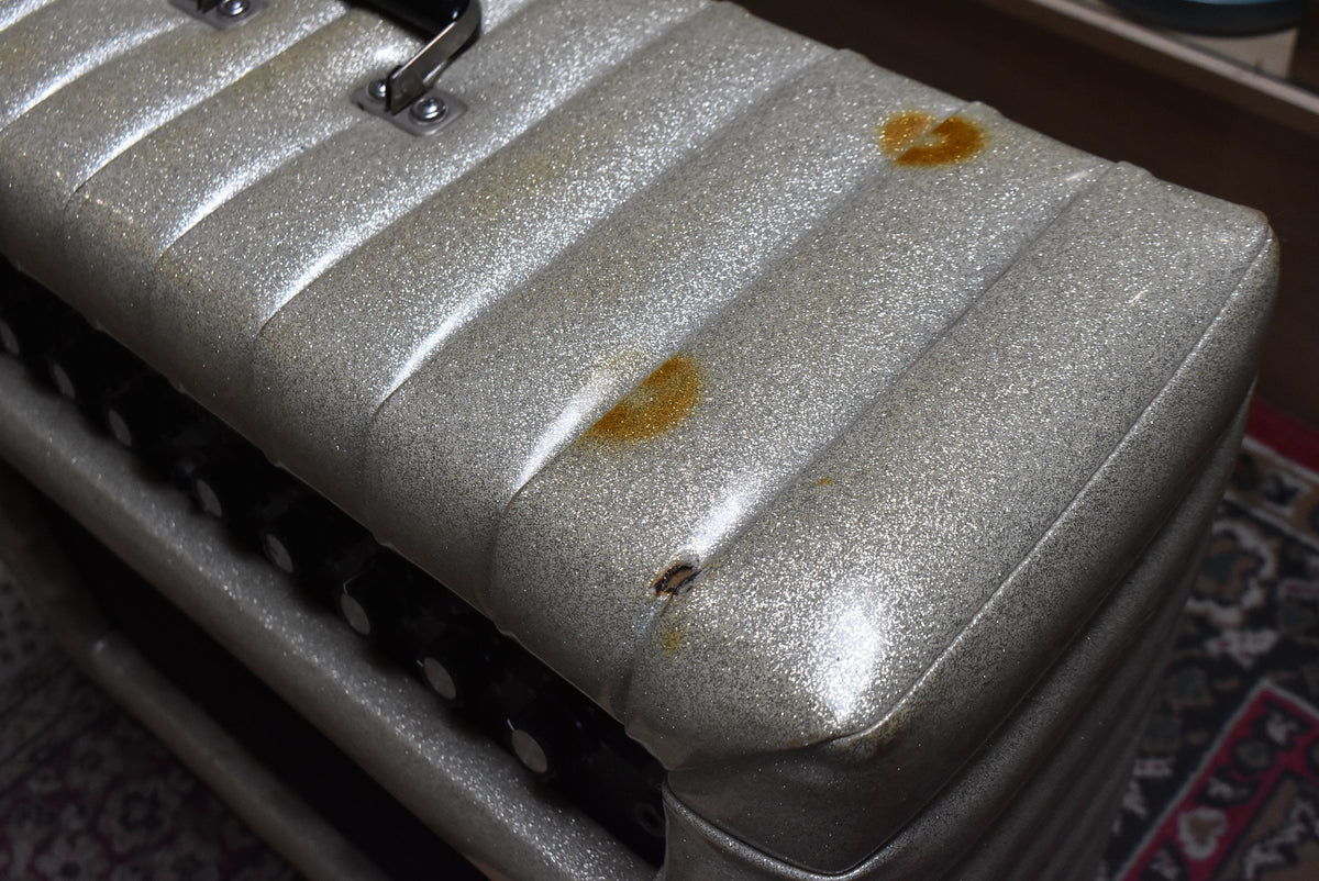 Close-up of the silver sparkle tuck-and-roll top, showing two large rust-colored stains and a small tear near the front edge.