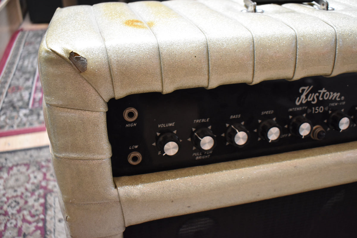 Close-up of the amp's top left corner, showing a tear in the sparkly silver tuck-and-roll covering and the black control panel with silver knobs.