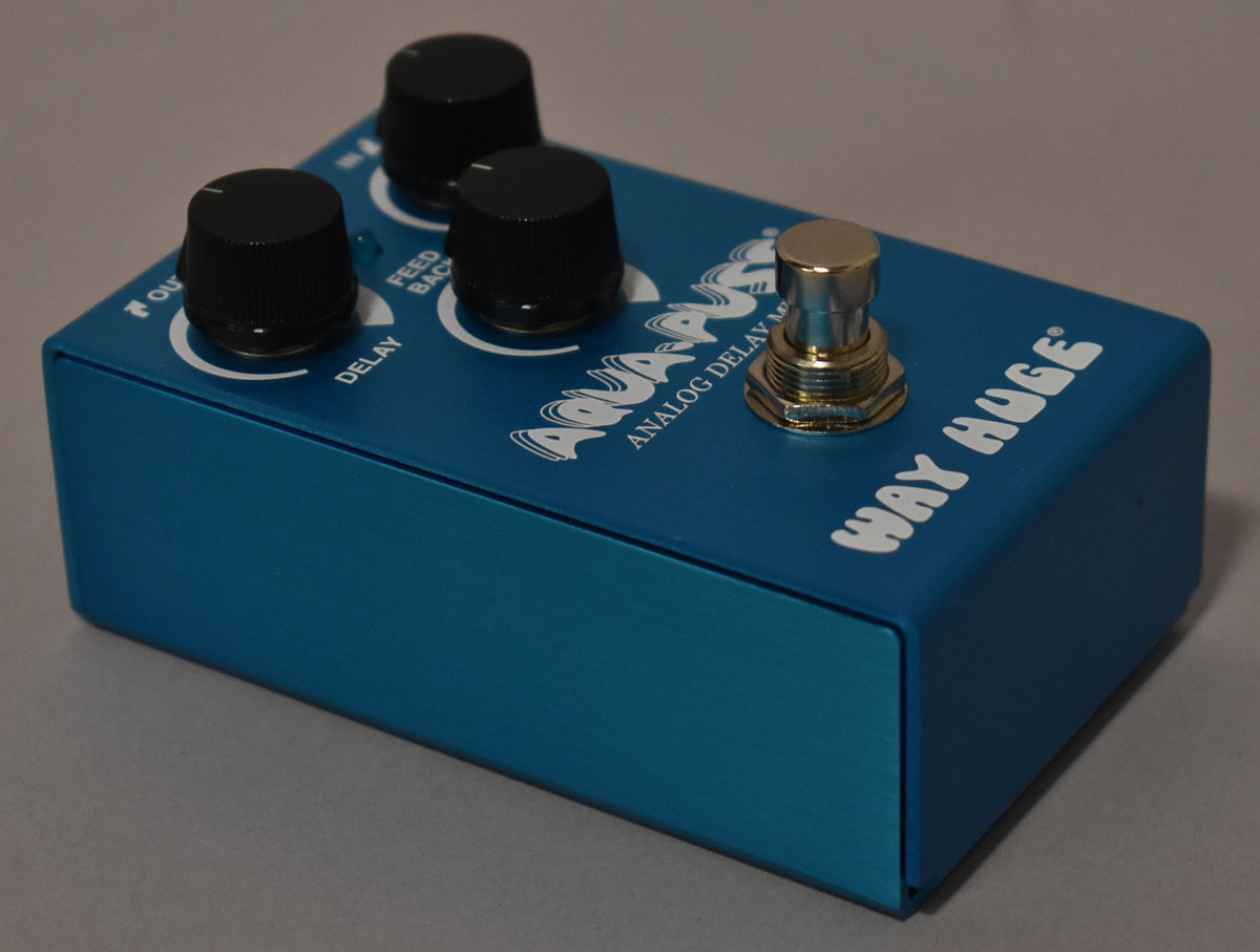A turquoise pedal with three black knobs, a gold footswitch, and white lettering, viewed from the top-right.