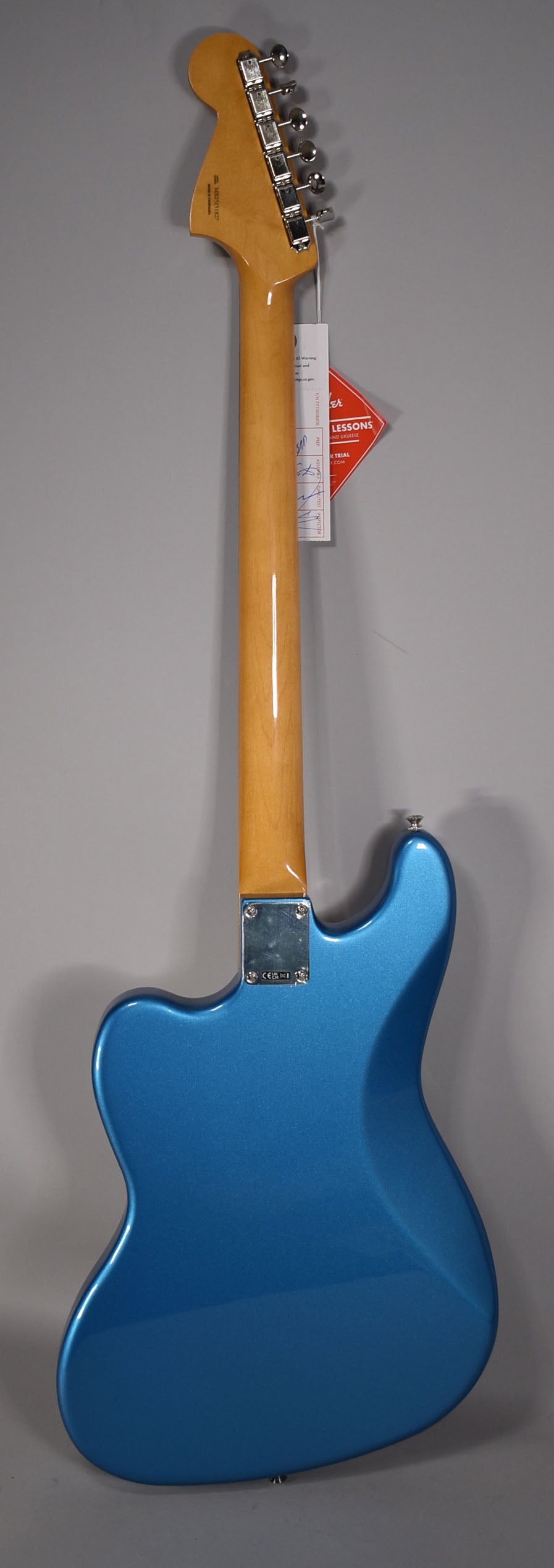 The back of a metallic Lake Placid Blue Bass VI, showing the glossy maple neck, chrome tuners, and neck plate.
