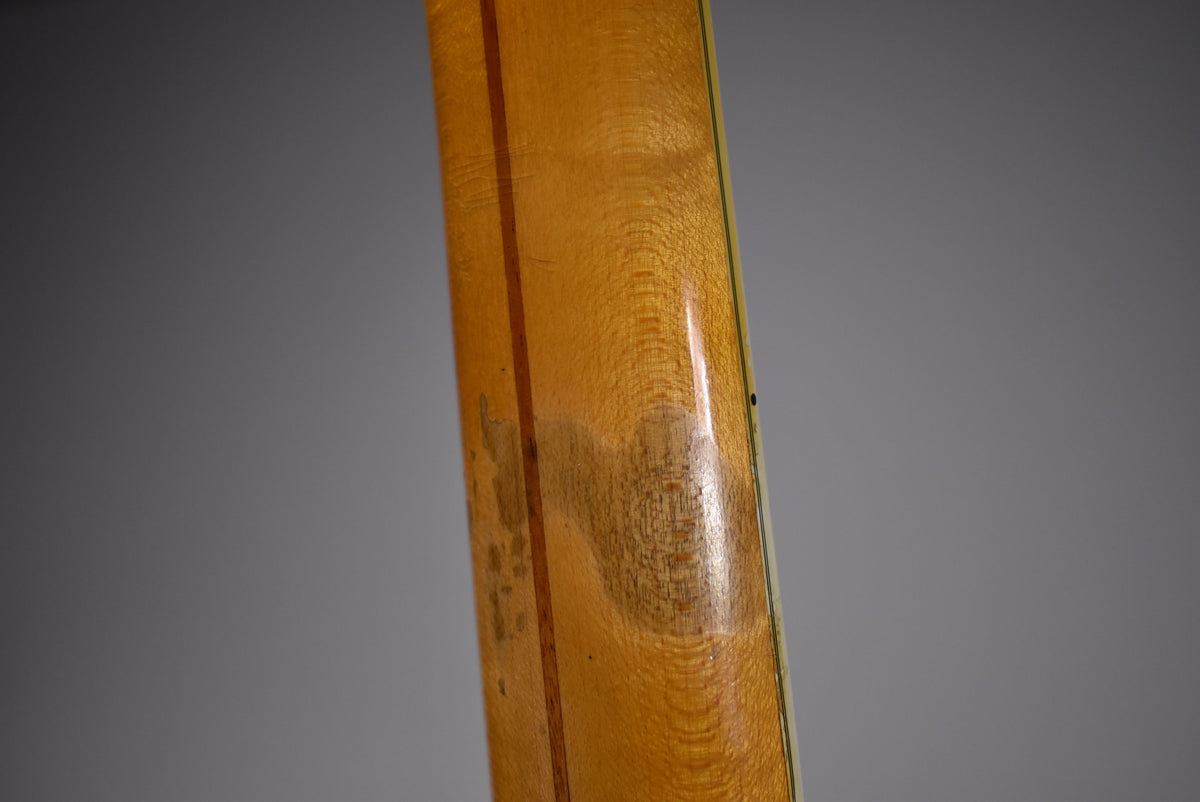 Close-up of the guitar's blonde neck, showing a worn, darkened patch on the back and a thin dark stripe down the center.