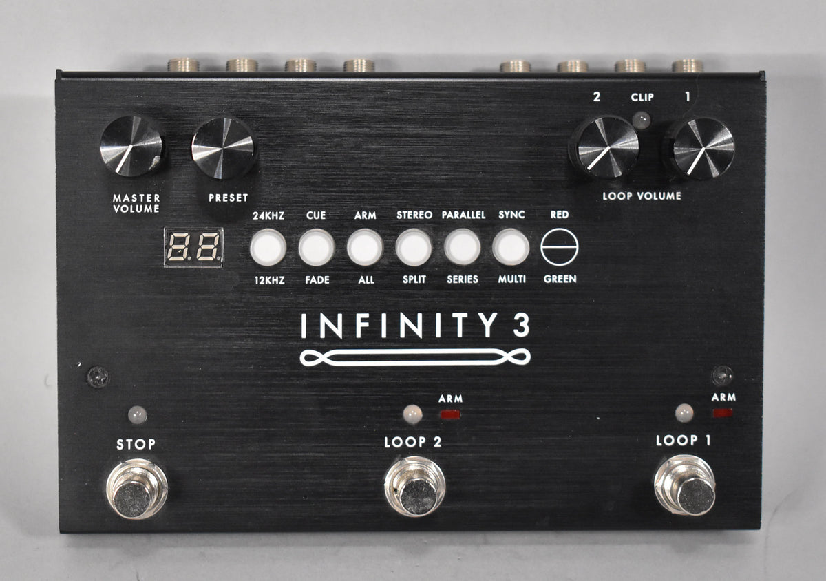A black brushed metal pedal with four large knobs, eight white buttons, three footswitches, and a small digital display.
