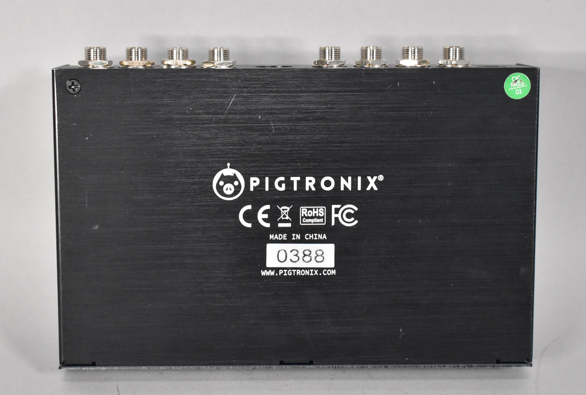 The pedal's brushed black metal back panel is shown, featuring eight silver jacks along the top edge and a green "pass" sticker.