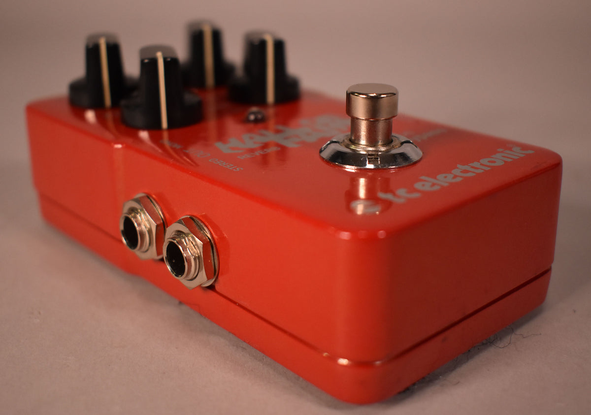 The bright red pedal is angled to show its left side with two input jacks and the chrome footswitch on the top.