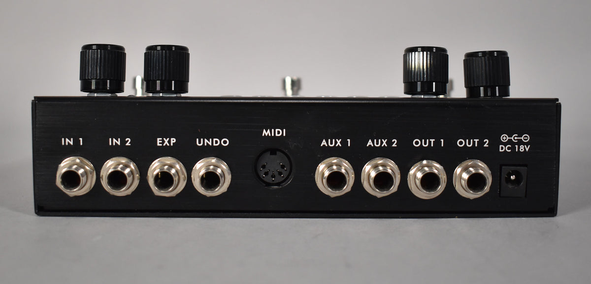 Rear view of the black pedal, showing 8 silver 1/4" jacks, a 5-pin MIDI port, and a DC 18V power input.