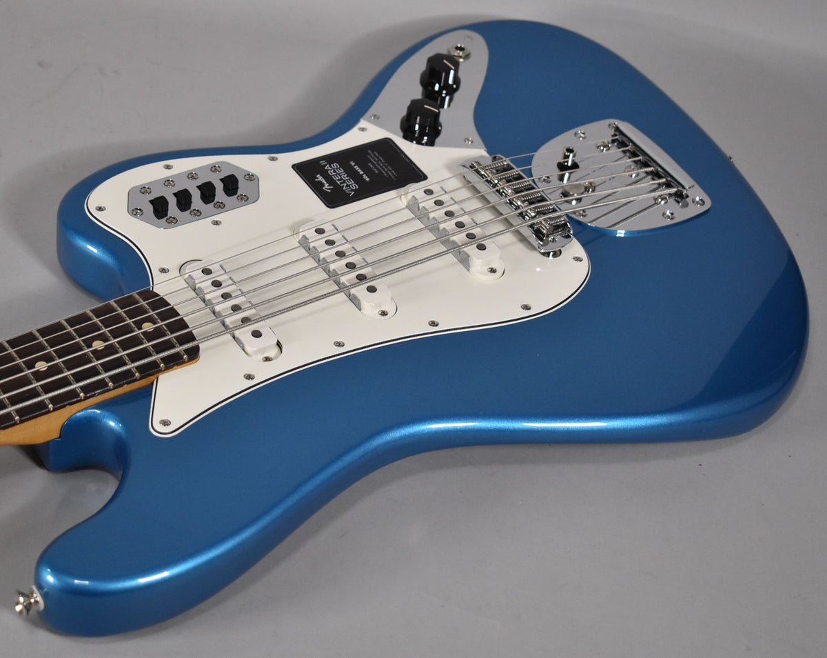 Angled close-up of the metallic blue Bass VI body, showing its white pickguard, chrome bridge, and four black control knobs.