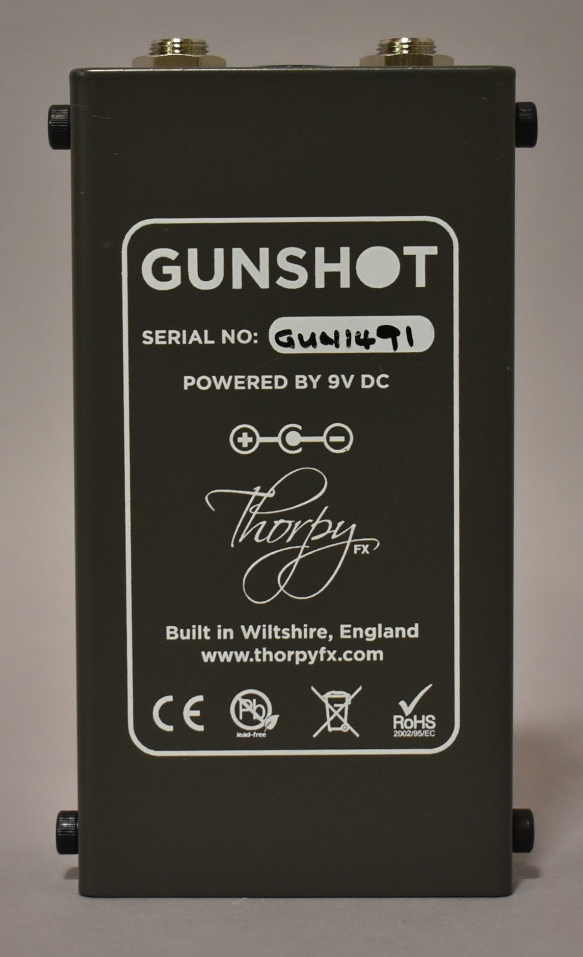 The pedal's dark gray underside is shown, with a white rectangular label detailing power requirements and manufacturing information.