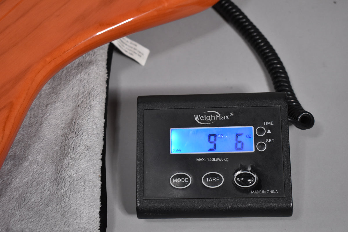 A WeighMax scale displays "9.6" in blue, next to a translucent orange bass body resting on a gray cloth.