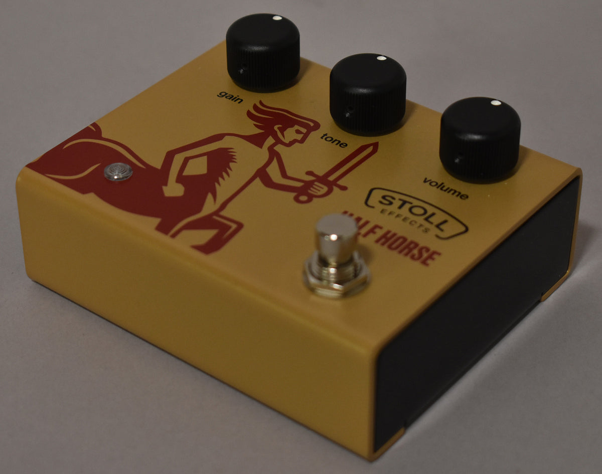 The gold pedal, angled from the front-right, has a red centaur graphic, three black knobs, and a silver footswitch.