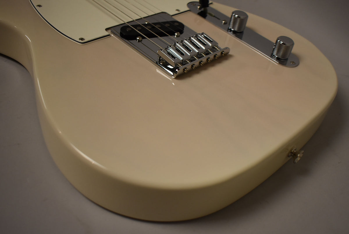 Close-up of the guitar's lower body, showing the White Blonde finish, chrome bridge, black bridge pickup, and two knurled control knobs.