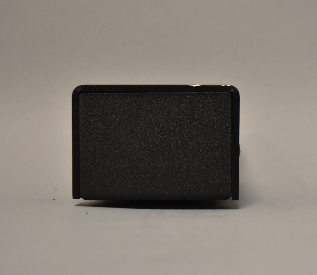 The black textured pedal is viewed from the side, showing a small chip on the top left edge.