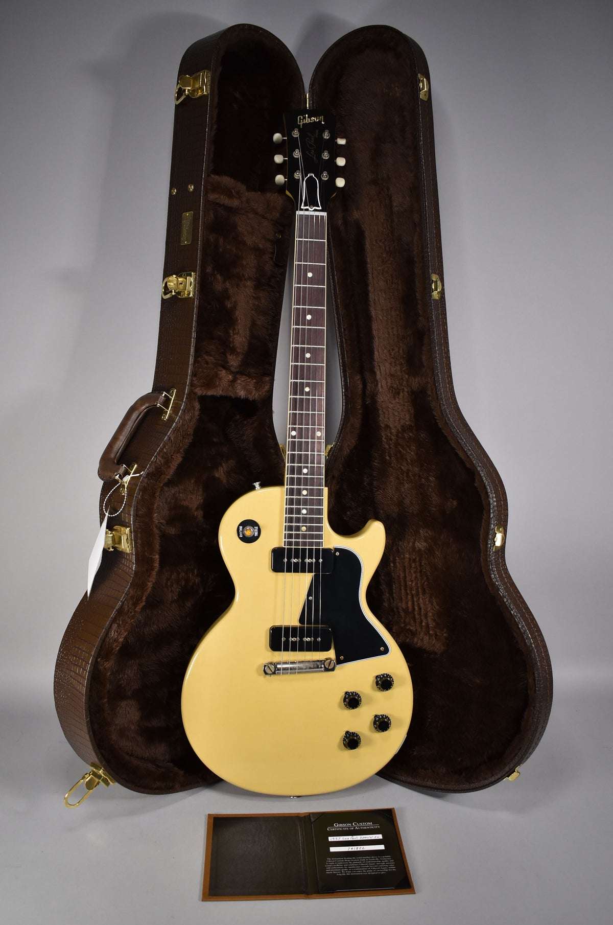 Full-length view of a TV yellow single-cut guitar with two P90 pickups, black pickguard, and four black knobs, standing in its open brown case.