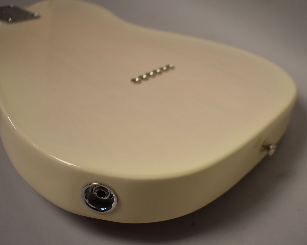 The back of a white blonde Telecaster body, showing the chrome string-through-body ferrules and output jack.