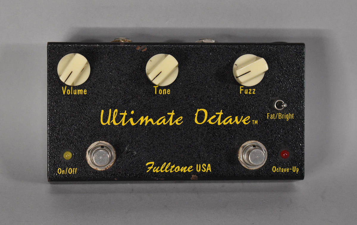 Black textured pedal with three cream knobs, two footswitches, a toggle switch, and two small indicator lights, showing some wear.