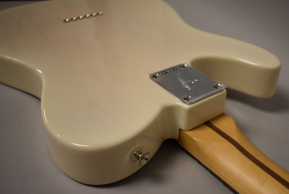 The guitar's white blonde body, viewed from the back, shows a chrome neck plate, strap button, and six string-through-body ferrules.