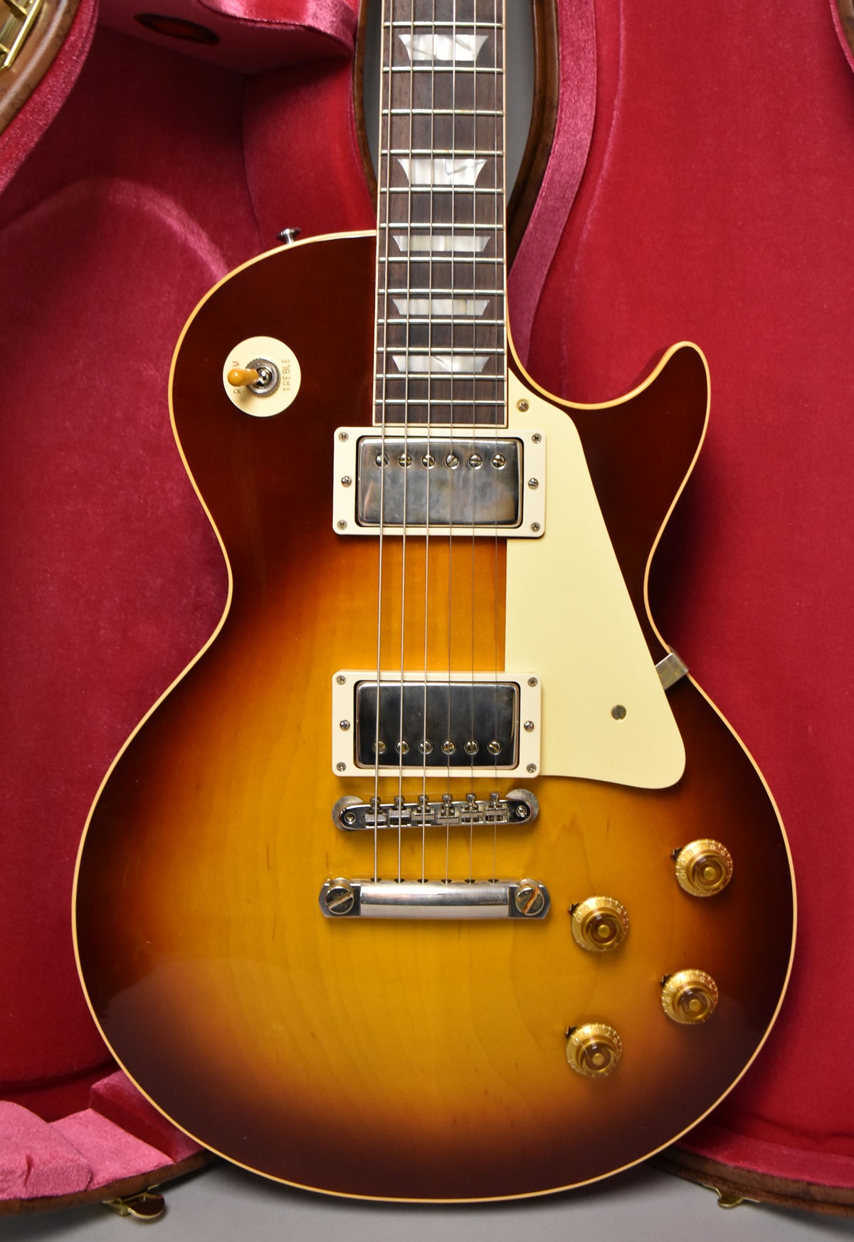 Full-frame, top-down view of the Bourbon Burst Les Paul, showing its two humbuckers, cream pickguard, and gold top hat knobs.