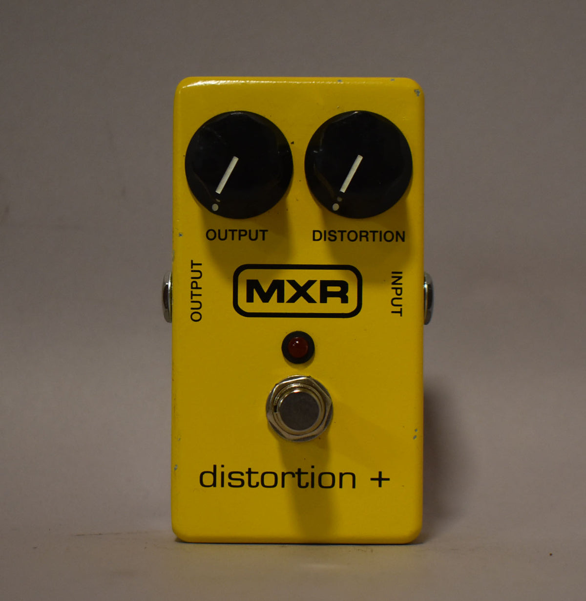 Yellow rectangular pedal with two black knobs, a red LED, and a silver footswitch, viewed from directly above.