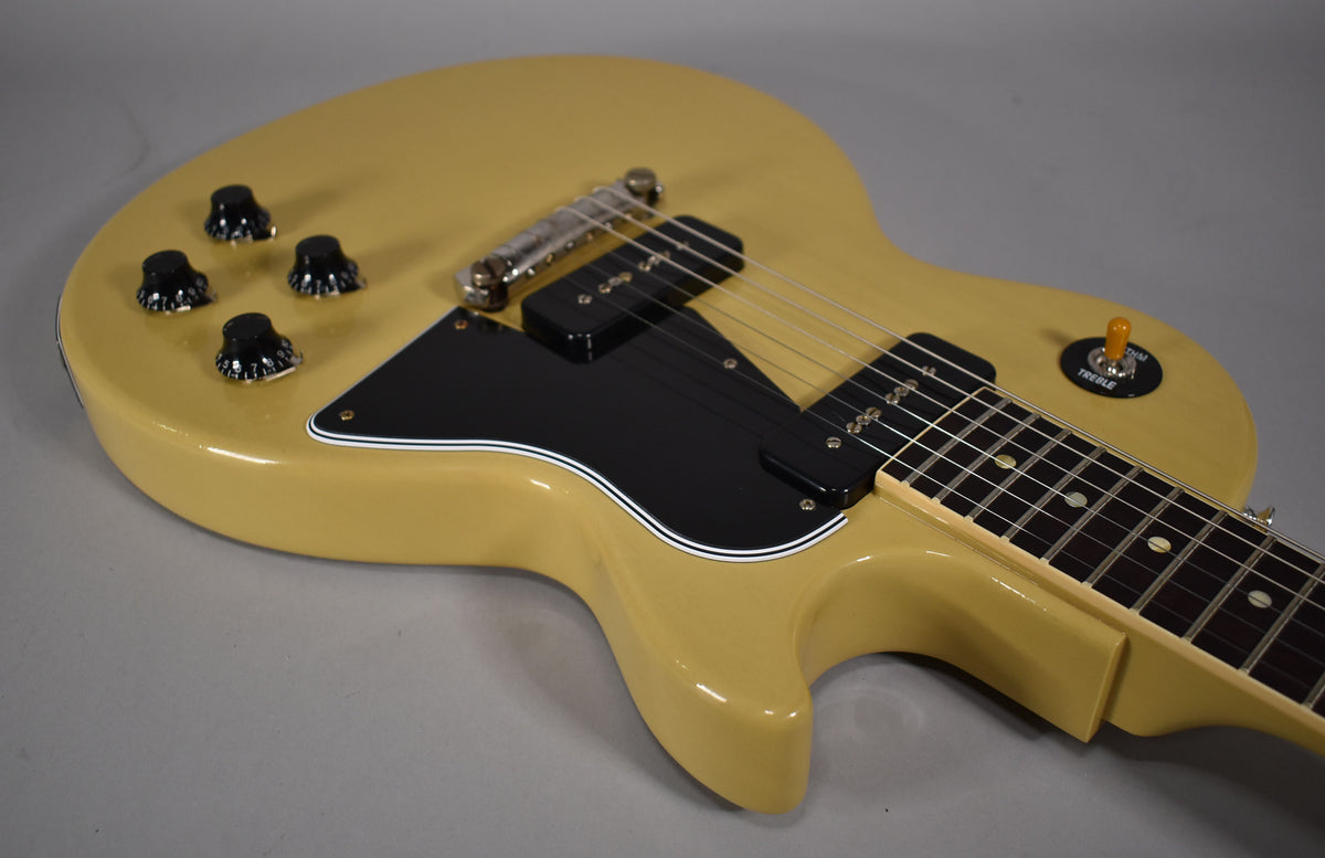 The TV yellow single-cut guitar body is angled from the lower left, showing its black pickguard, two P90 pickups, and four black control knobs.