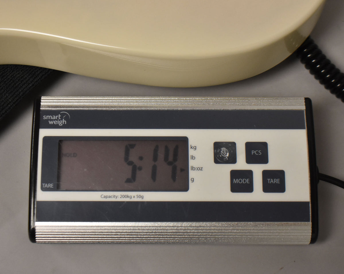 The White Blonde Telecaster's lower bout rests on a digital scale displaying "5:14" in pounds and ounces.