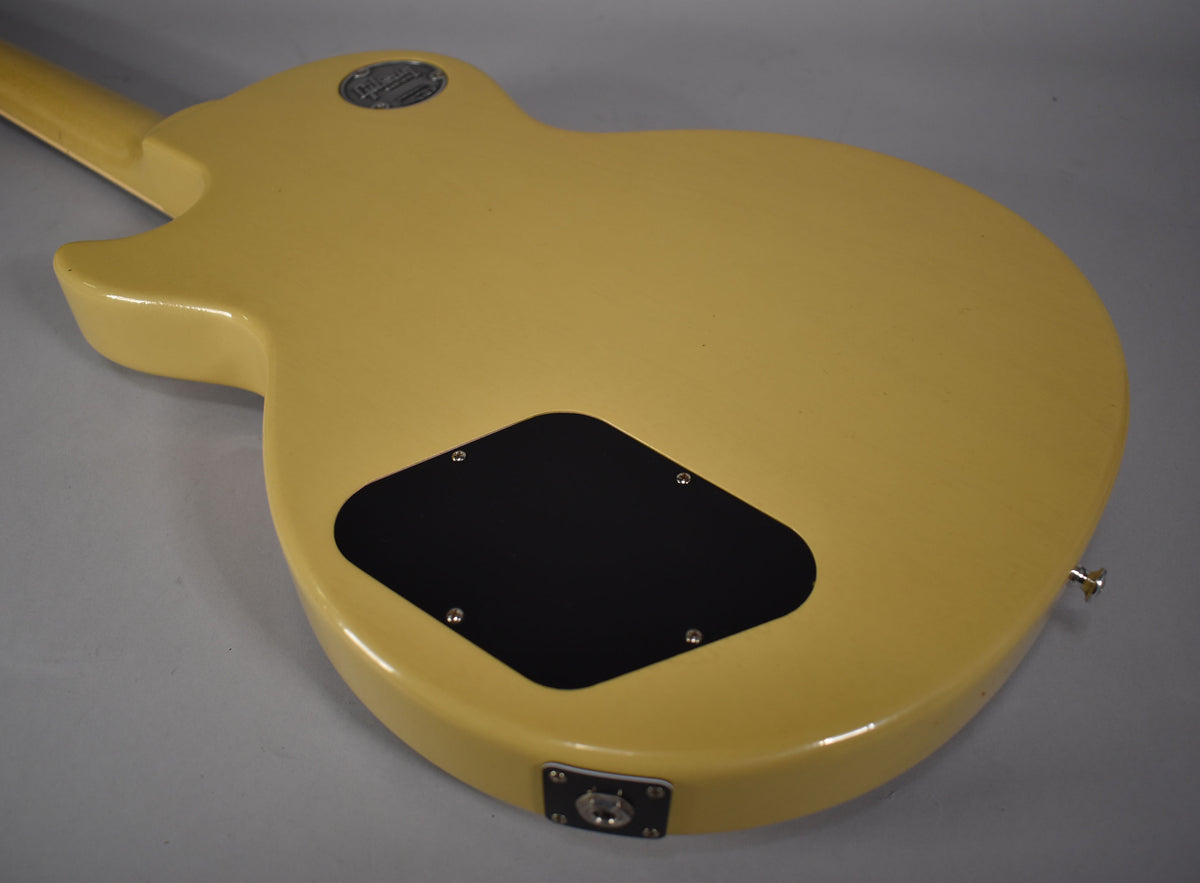 The back of the TV yellow guitar body, showing the black control cavity cover, output jack, and a strap button.