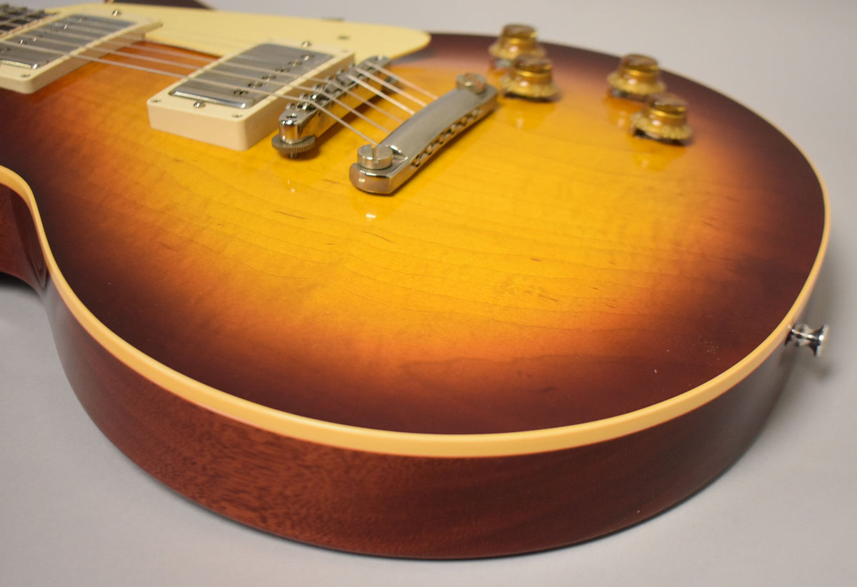 Close-up of the guitar's lower body, showing the Bourbon Burst finish, cream binding, nickel hardware, and four amber control knobs.