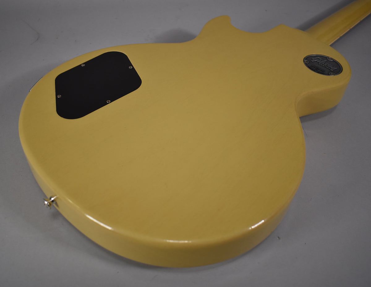 The back of the TV Yellow guitar body is visible, showing a black control cavity cover, a strap button, and a metal medallion near the neck joint.