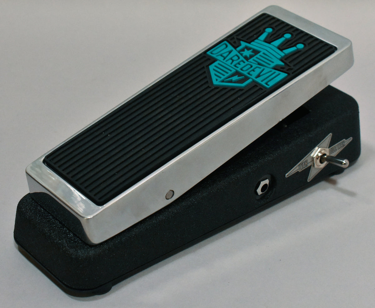 The black textured pedal has a chrome rocker with a ribbed rubber pad and a teal logo, plus a star-shaped toggle switch on the side.