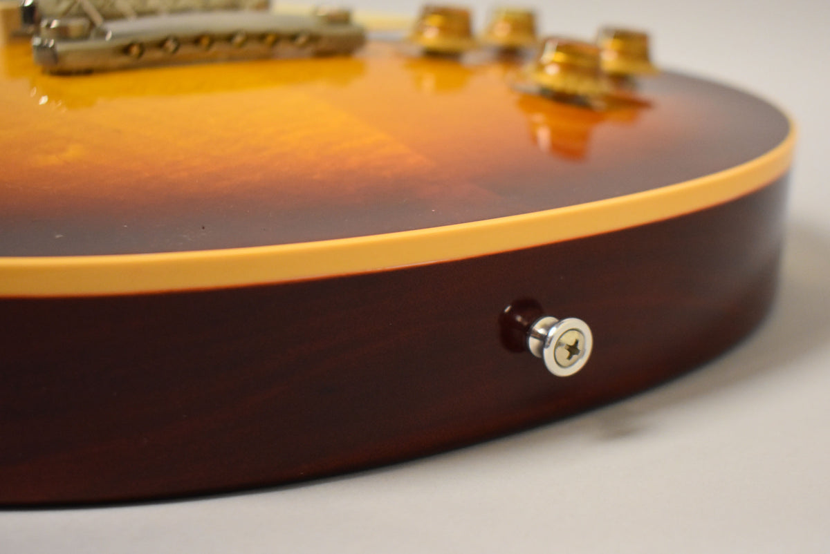 Close-up of the guitar's lower bout, showing the dark brown back, cream binding, and the chrome strap button on the side.