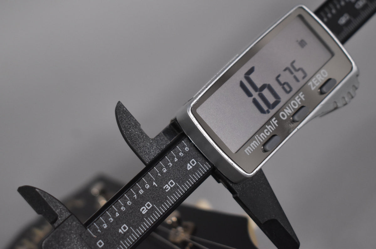 A digital caliper measures the nut width at 1.675 inches on the TV Yellow Les Paul Special's dark headstock.