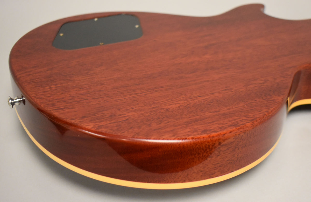 The back of the guitar, angled from the lower bout, shows the dark red Bourbon Burst finish with wood grain and a black control cavity cover.