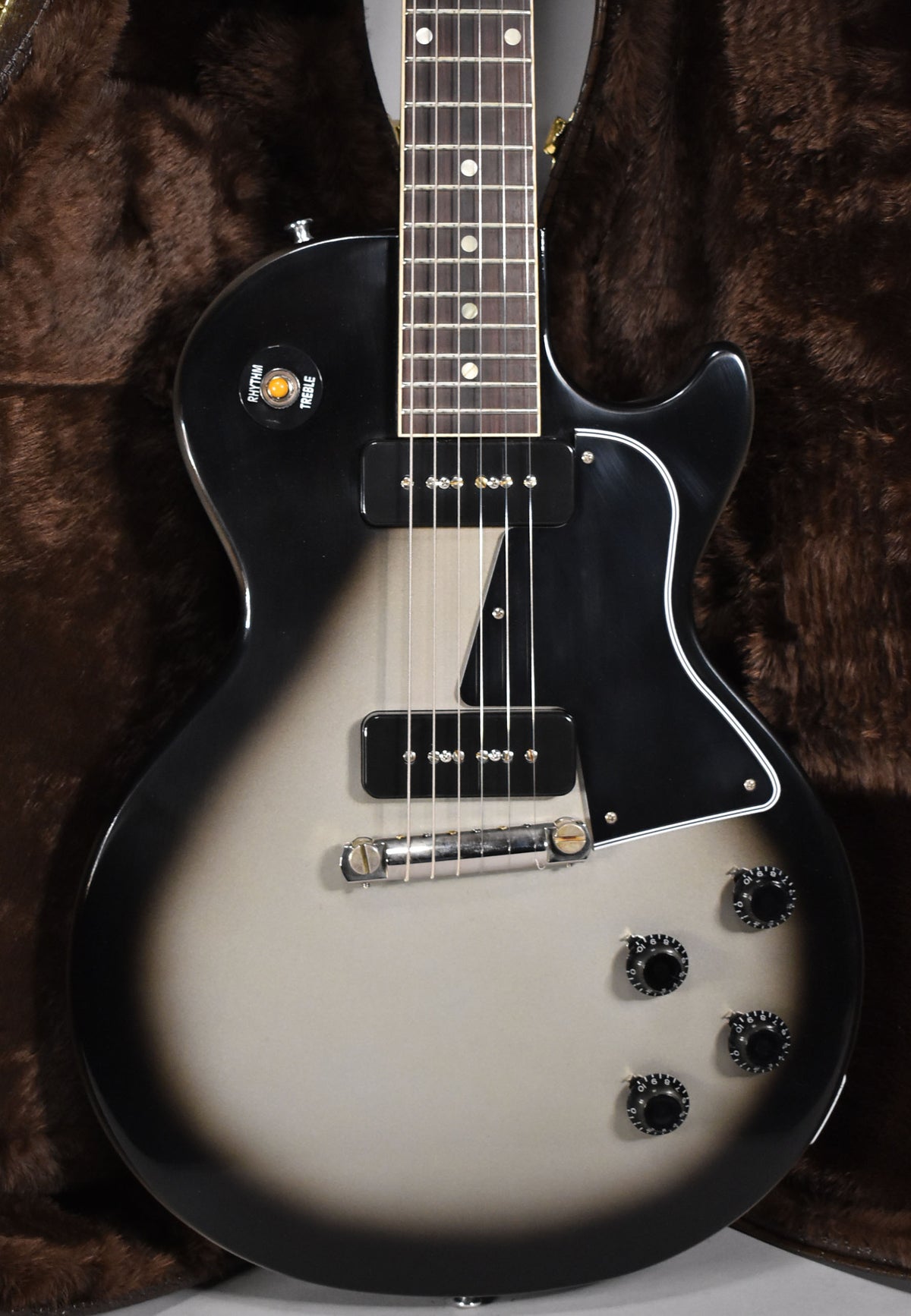 The silverburst guitar body, with two black P90 pickups and four black control knobs, is angled slightly right.
