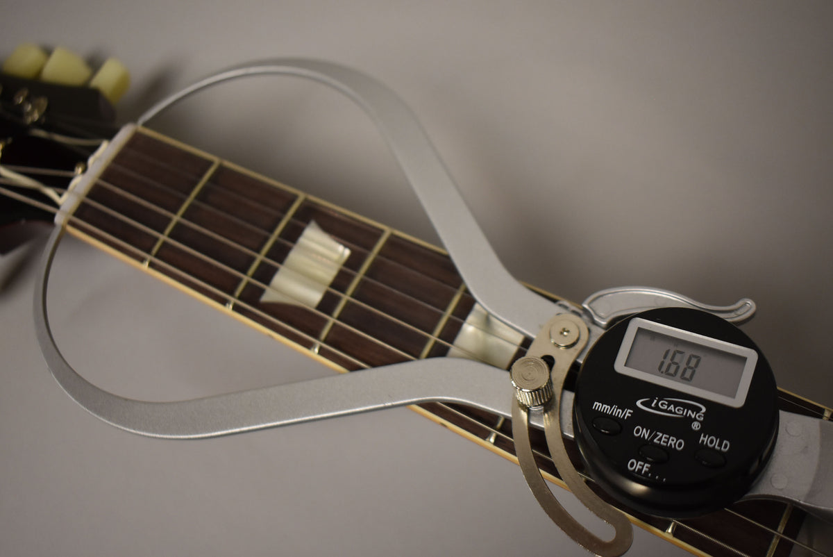 A digital caliper measures the nut width of the dark rosewood fretboard with trapezoid inlays, displaying "1.68".