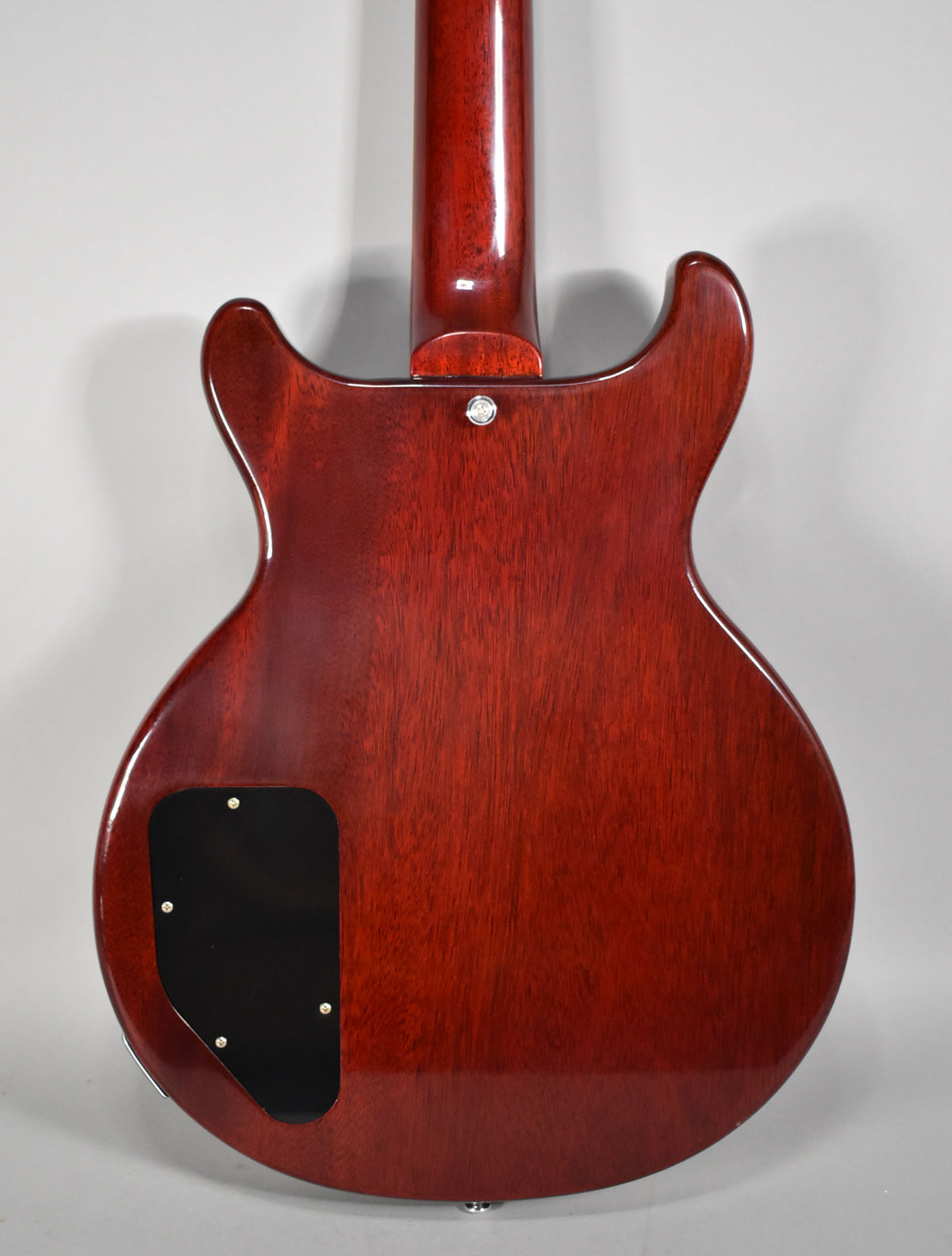 The guitar's cherry red back shows wood grain, a black control plate, and a neck joint with a strap button.