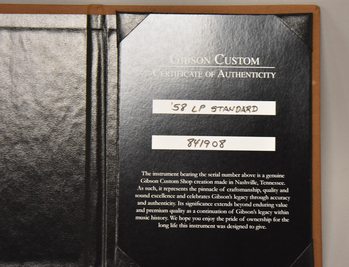 A close-up of the open black leatherette Certificate of Authenticity booklet, showing the text and serial number.