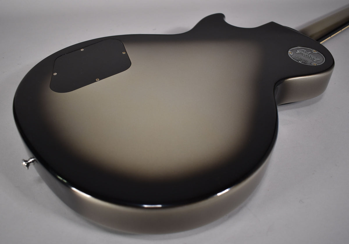 The guitar's back, angled from the lower bout, shows a silverburst finish, black control cavity cover, and a chrome strap button.