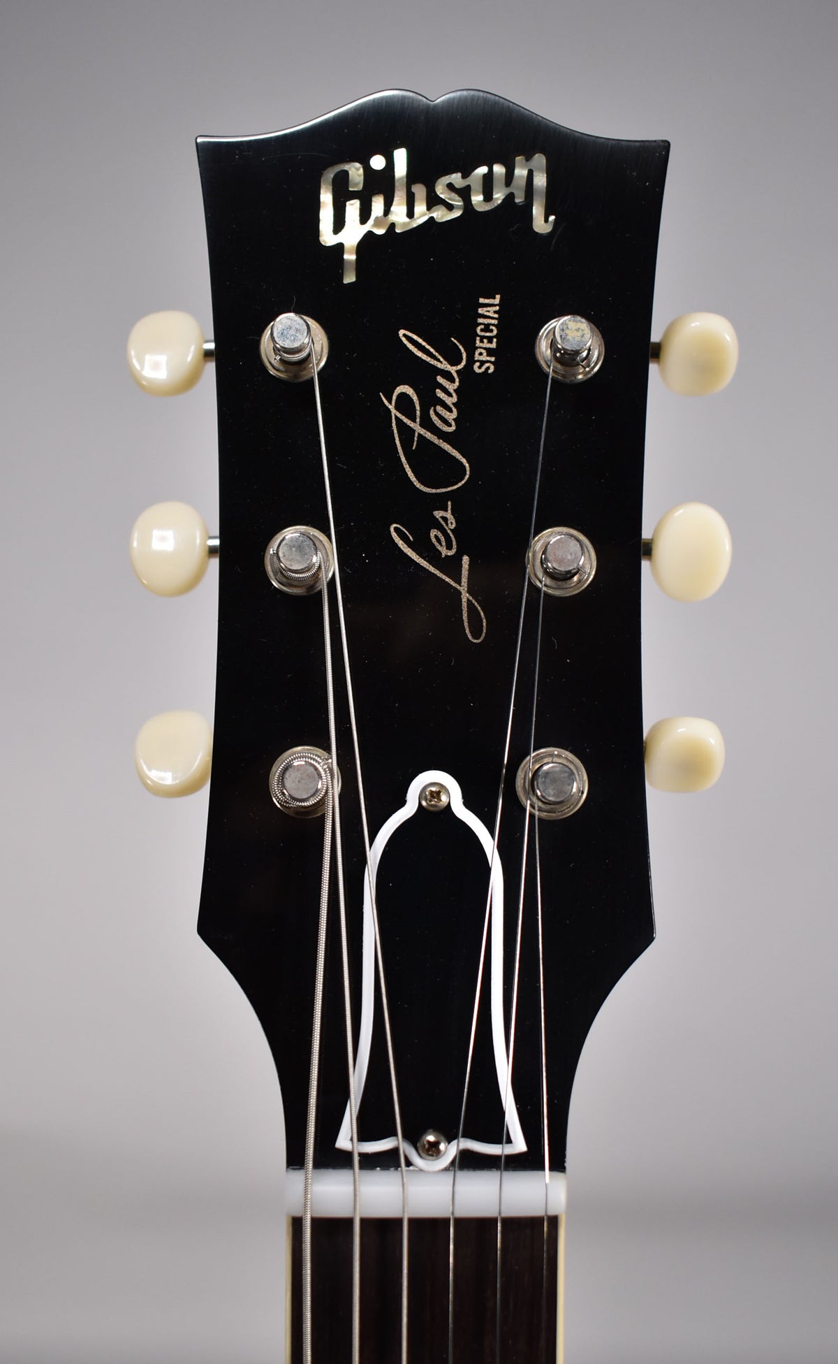 The black headstock, with cream tuning pegs, is framed from the top, showing the truss rod cover and nut.