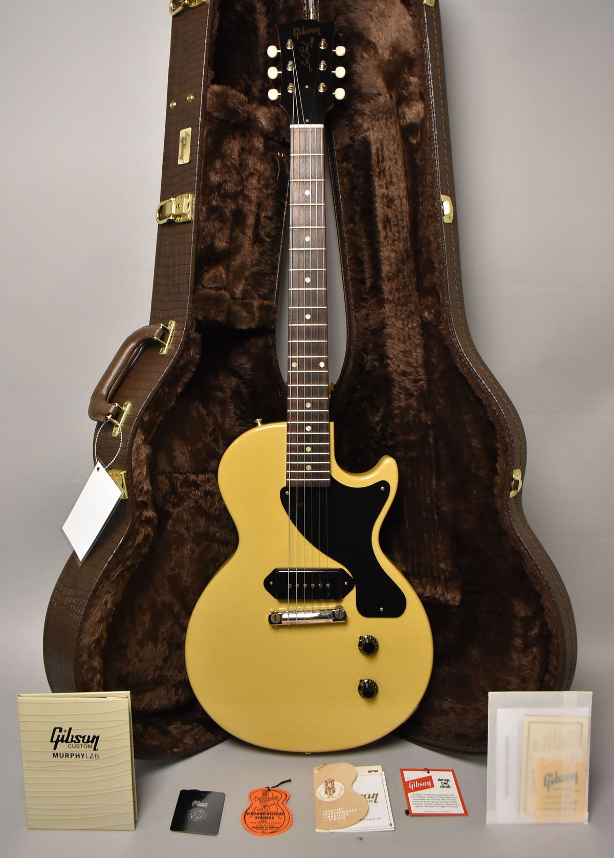Full-length view of a TV Yellow single-cut guitar with a black pickguard, P90 pickup, and two black knobs, standing in a brown fur-lined case.