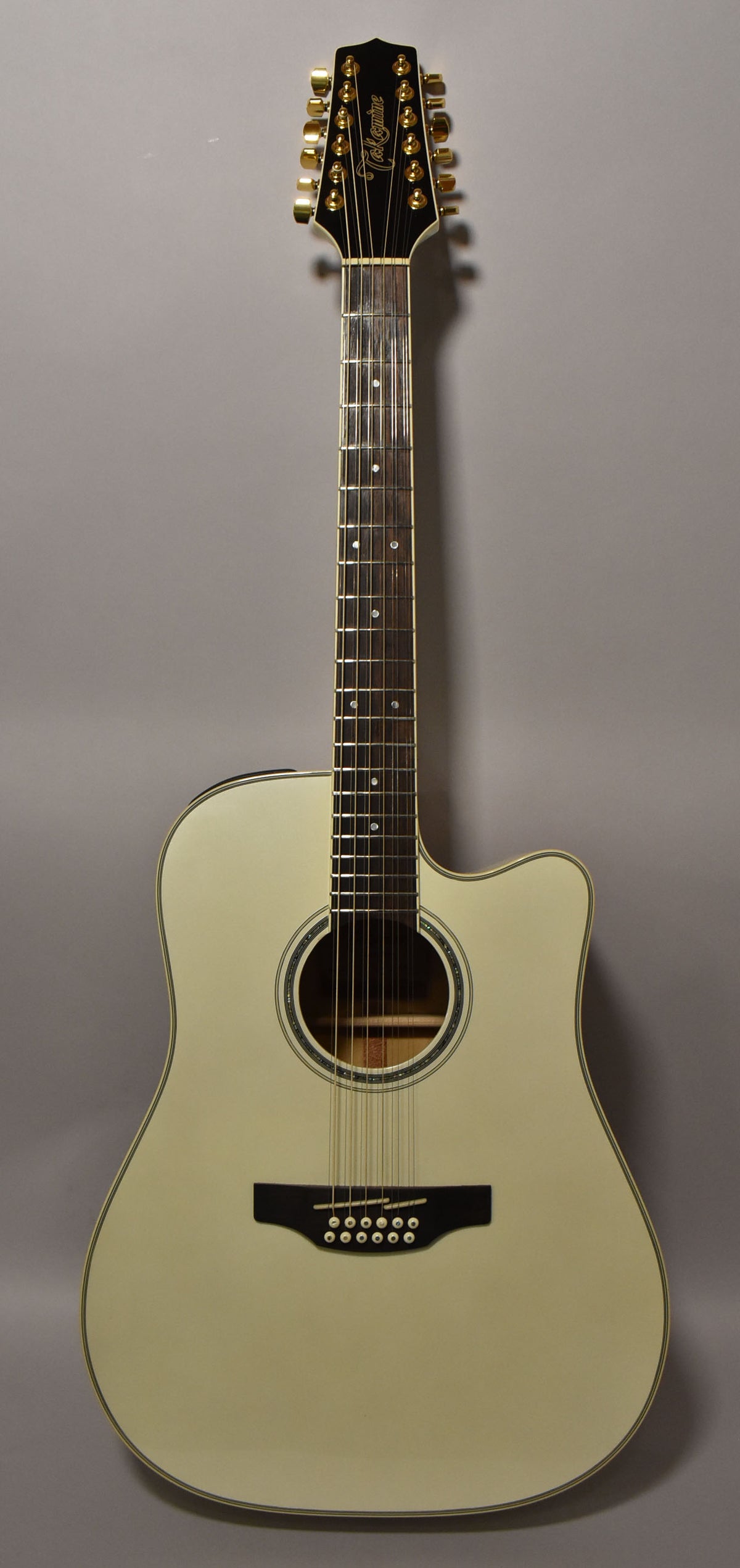 Full-length view of a pearl white 12-string acoustic-electric guitar with a cutaway body, dark fretboard, and gold tuners.