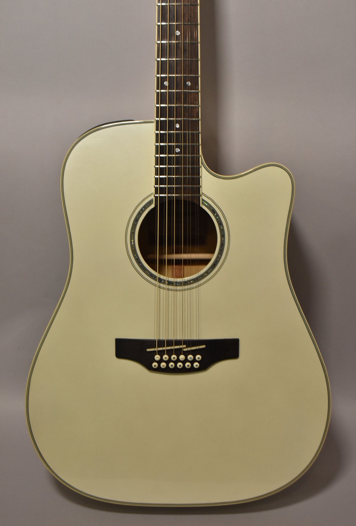 Full front view of a pearl white 12-string dreadnought acoustic-electric guitar with a cutaway and dark wood bridge.