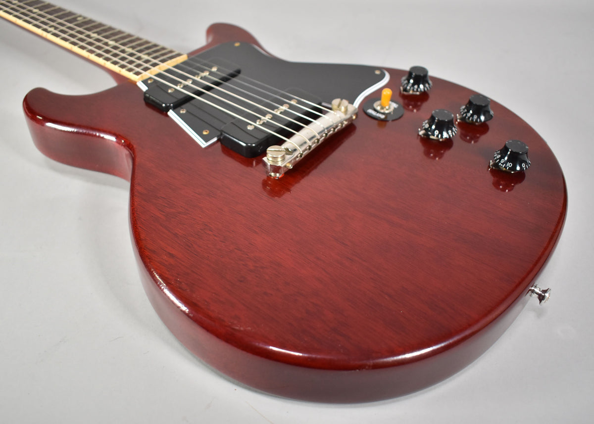 Cherry red double-cut guitar body, angled from the lower bout, showing two black P90 pickups, a black pickguard, and four black control knobs.