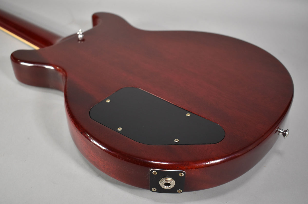 The cherry red guitar's back shows a black control cavity cover, output jack, and a chrome strap button.