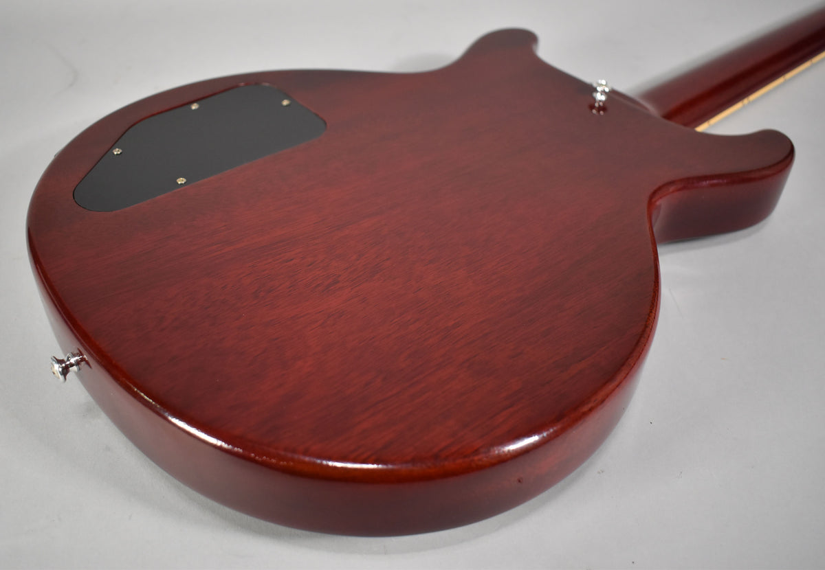 Rear view of the cherry red guitar body, showing the control cavity cover, wood grain, and two chrome strap buttons.