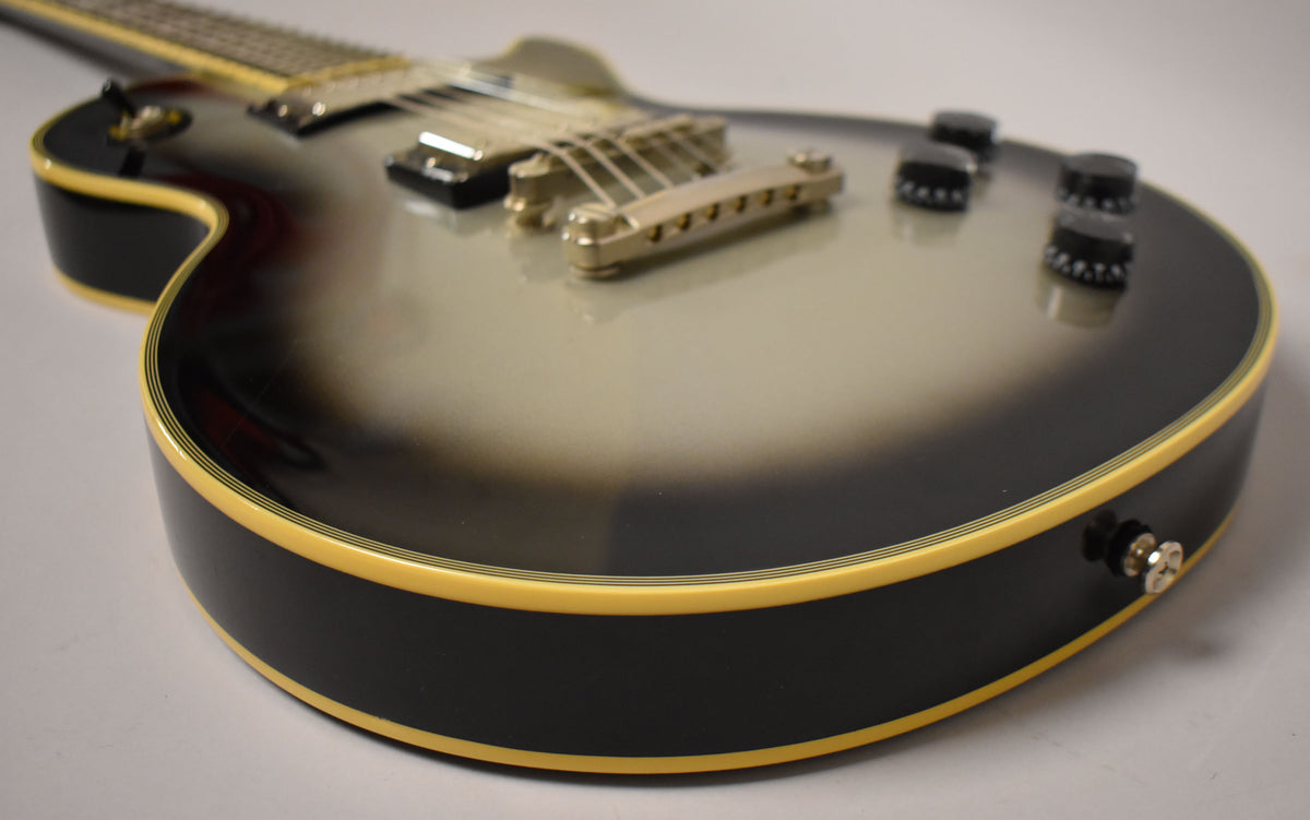 Close-up of the guitar's lower body, showing the silverburst finish, gold hardware, four black control knobs, and cream binding.