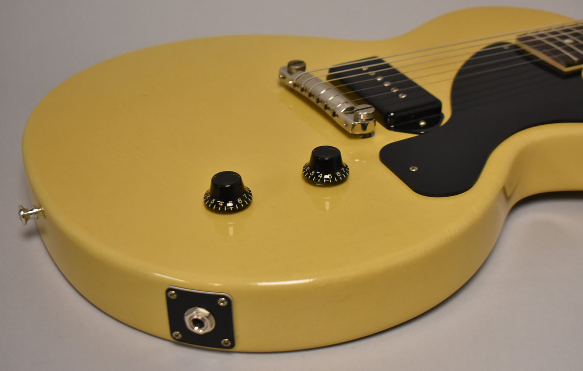 The TV Yellow guitar body, with light finish checking, shows two black control knobs, a black pickguard, and a chrome bridge and tailpiece.