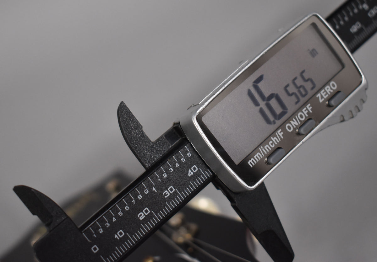 A digital caliper measures the nut width at 1.6565 inches, with the guitar's cherry red finish visible below.