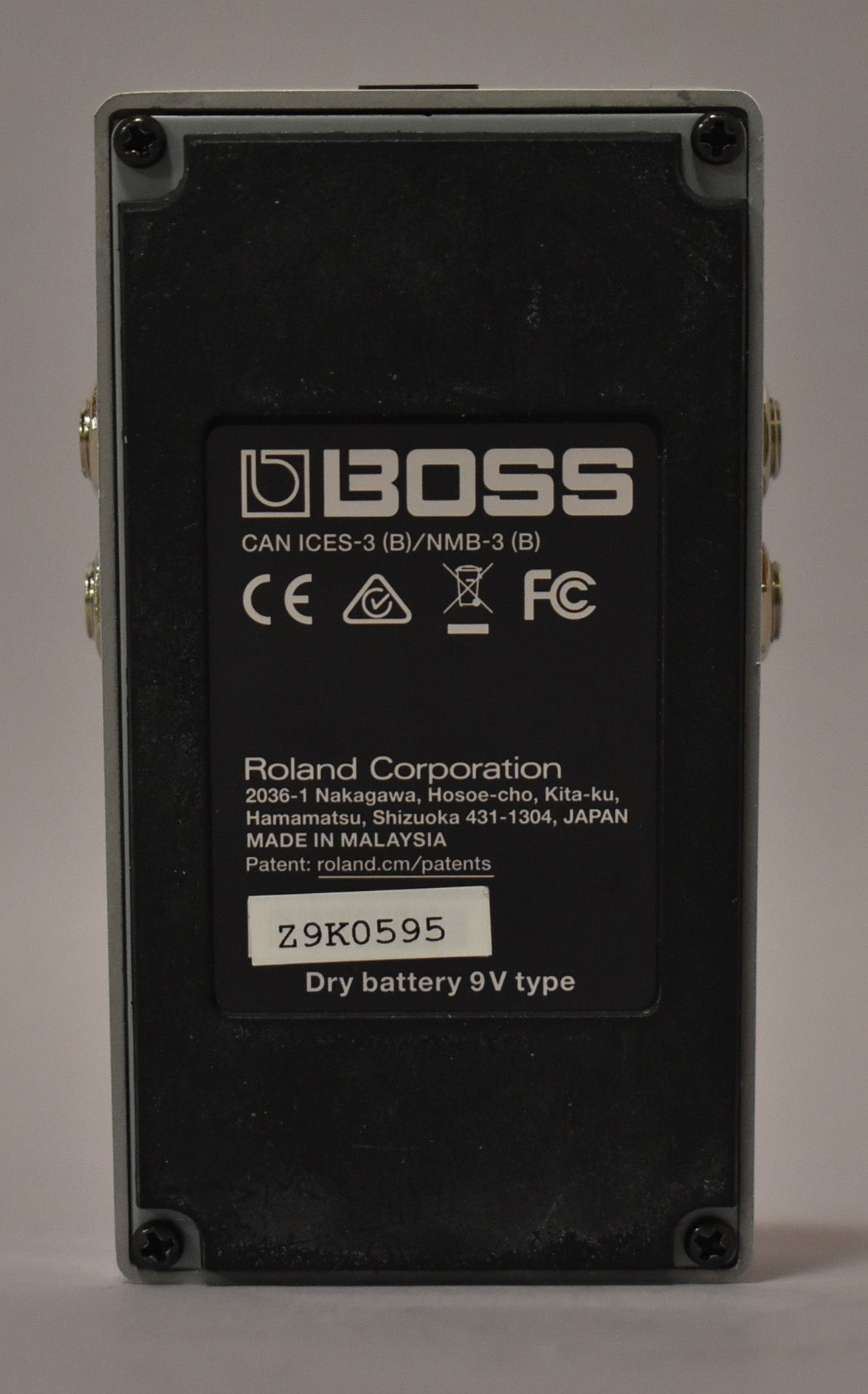 The pedal's gray bottom plate is visible, with a black rectangular label covering most of it, showing light scuffs and dust.